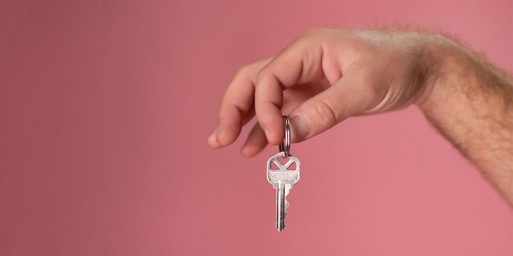 Home-Guarantee-Access Hand holding a key over a pink background